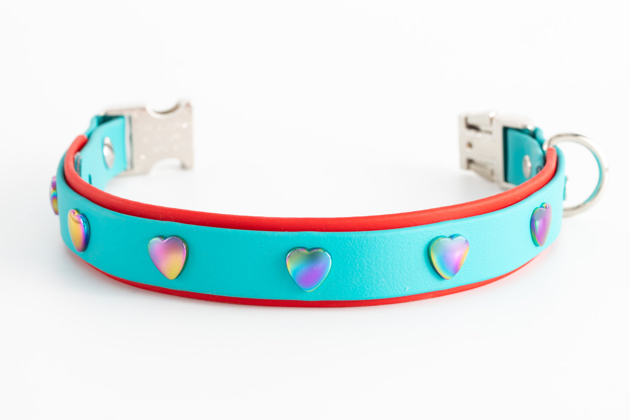 A red and blue biothane dog collar with a metal buckle and rainbow hearts pattern.